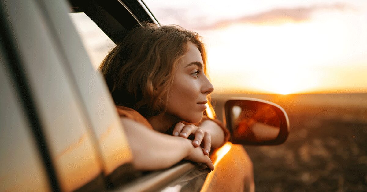 Woman looking out a car window while waiting to confirm a pregnancy test result and considering her next steps.